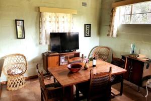 a dining room with a wooden table and a television at 10 guest stay in the mountains of Nyanga! in Juliasdale