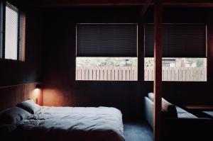 a bedroom with a bed and two windows at MAGATAMA.INN in Sumoto