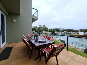 una mesa y sillas en un balcón con vistas al agua en Marina House, en Port Alfred