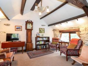 a living room with a grandfather clock and chairs at Cranesbill Barn in Kirkby Stephen