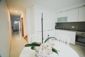 a white kitchen with a table with a plant on it at CASA DA RIBEIRA in Viana do Castelo