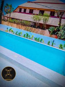 una piscina blu con una casa sullo sfondo di MAISON FLORAL a Saly Portudal