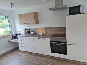 a white kitchen with a sink and a refrigerator at Ferienwohnung am Rursee in Simmerath