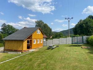 a small wooden cabin with a picnic table in a yard at Chata Pod kaplí in Sloup