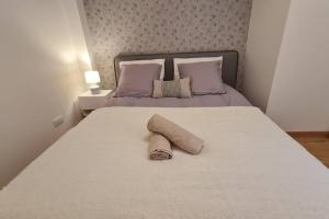 Una cama blanca con una toalla enrollada. en L'océan Parc, Libourne Hypercentre, Clim, Netflix, en Libourne