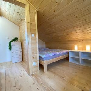 1 dormitorio pequeño con 1 cama en una habitación de madera en Chata Pod kaplí, en Sloup