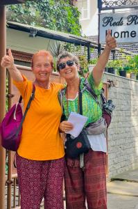 twee oudere vrouwen die naast elkaar staan met hun handen omhoog bij Reds Residency - Homestay in Cochin