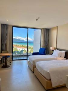 two beds in a hotel room with a view of the ocean at The Arena Cam Ranh Resort all Luxury Service in Miếu Ông