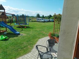 a yard with a playground with a slide and a chair at Domki Afrodyta in Jarosławiec