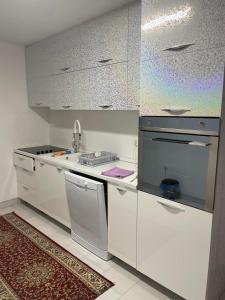 a white kitchen with a stove and a sink at Apartman SARA in Sarajevo
