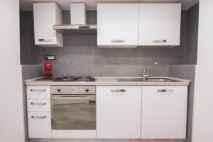 una cocina blanca con armarios blancos y fregadero en [Centro Storico] Luxury Suites, en Nápoles
