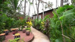a garden with stools and a house with trees at Tranquil Beach Resort in Harihareshwar