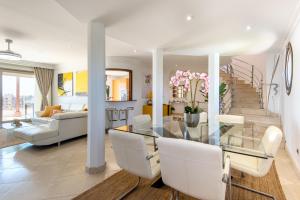 a living room with a glass table and white chairs at PH BELLAGIO: Luxurious and Romantic duplex penthouse with PRIVATE POOL & sea views in Benalmádena