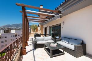 a patio with couches and a table on a balcony at PH BELLAGIO: Luxurious and Romantic duplex penthouse with PRIVATE POOL & sea views in Benalmádena