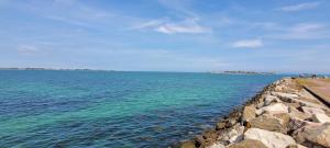 a large body of water with a stone wall at Gîte la rose des vents N 1 in Saint-Vaast-la-Hougue