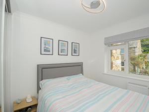 a white bedroom with a bed and a window at Wheal Charlotte Cottage in Penzance