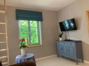 ein Wohnzimmer mit Fernseher und einem Tisch mit Blumen in der Unterkunft Oak House in Świebodzin