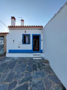 un edificio blanco y azul con un patio de piedra en Janelas de Monsaraz en Telheiro