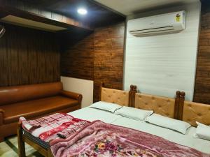 a bedroom with a bed and a couch and a air conditioner at Hotel Shubhadra Guest House in Mathura