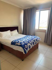 Un dormitorio con una cama con una manta azul y una ventana. en Shengtang Business Hotel, en Johannesburgo 42 fotos más