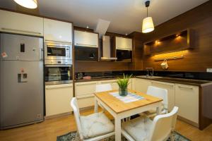 eine Küche mit einem Holztisch und weißen Stühlen in der Unterkunft Apartments PRN in Pristina