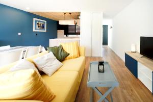 a living room with a yellow couch and a table at Etxe Ttippi in Saint-Jean-de-Luz