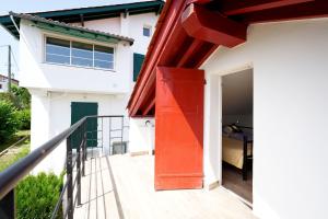 une porte rouge sur le côté d'une maison blanche dans l'établissement Etxe Ttippi, à Saint-Jean-de-Luz