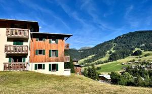 une maison sur une colline avec des montagnes en arrière-plan dans l'établissement ULVF Les Essertets, à Praz-sur-Arly