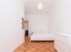 una camera bianca con letto e pavimento in legno di HOUZE_4 room flat in Lisbon Centre near Zoo a Lisbona