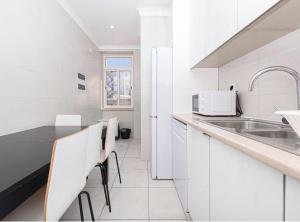 una cucina bianca con lavandino e armadietti bianchi di HOUZE_4 room flat in Lisbon Centre near Zoo a Lisbona
