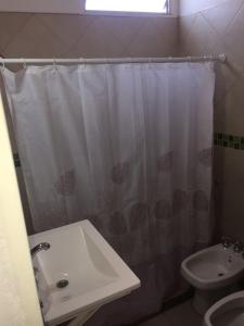 La salle de bains est pourvue d'un rideau de douche blanc et d'un lavabo. dans l'établissement Depto temporario carlos paz, à Villa Carlos Paz