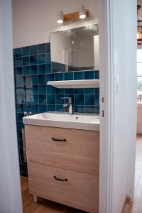 a bathroom with a sink and a blue tiled wall at Maison vue sur les alignements de Carnac - Les Glycines in Carnac