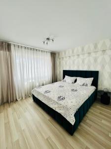 Schlafzimmer mit einem Bett mit einer schwarzen und weißen Bettdecke in der Unterkunft Panoramic M&M apartment in Suceava
