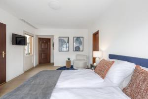 a white bedroom with a large bed and a tv at Ascona: Nostrana Apt. 3 in Ascona