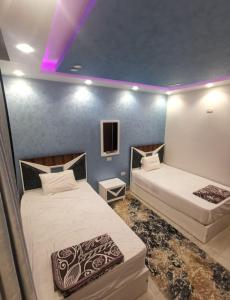 2 camas en una habitación con luces moradas en شقة مفروشة بالقاهرة مدينة المستقبل en Madīnat ash Shurūq