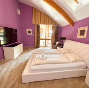 a bedroom with a white bed and purple walls at Lipno Holiday Penthouse in Lipno nad Vltavou