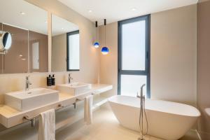 a bathroom with two sinks and a tub and a mirror at Eurostars Oasis Marbella in Marbella