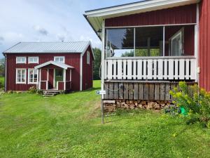 un granero rojo y una casa roja con porche en Lilly's house, Swedish High Coast, en Docksta