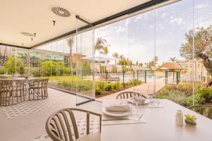a dining room with a table and chairs and a large window at Eurostars Oasis Marbella in Marbella