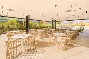 a restaurant with white tables and chairs and windows at Eurostars Oasis Marbella in Marbella