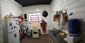 a small kitchen with a stove and a refrigerator at Casa Indaiá BnB - casa compartilhada in Caraguatatuba