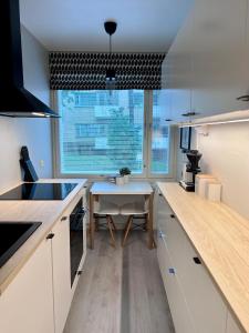 a kitchen with white cabinets and a table and a window at Kaksio Helsingissä omalla parkkipaikalla in Helsinki