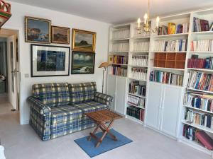 ein Wohnzimmer mit einem Sofa und Bücherregalen mit Büchern in der Unterkunft Penthouse mit Meerblick in Glücksburg