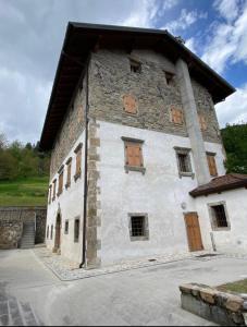 un gran edificio de piedra con puertas y ventanas de madera en Cjase Cjandin, en Cercivento