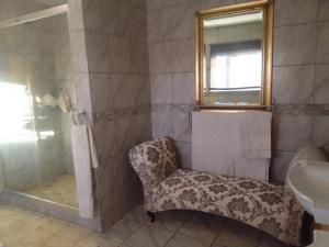a bathroom with a shower and a chair next to a sink at Chateau De Vie in Krugersdorp