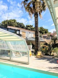 una piscina con una casa de cristal y una palmera en Joli haut de villa à deux pas de la mer et piscine, en Sausset-les-Pins