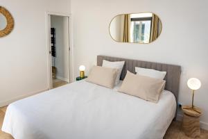 1 dormitorio con cama blanca y espejo en la pared en Villa Juliane, en Cadenet