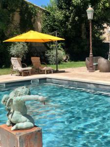 a statue in a swimming pool with an umbrella at Villa Pauline in Avignon
