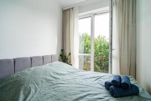 Una cama con dos toallas azules y una ventana. en Green Apartament Olsztyn, en Olsztyn
