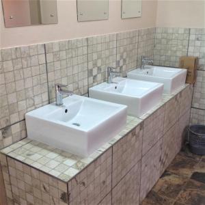 a bathroom with two sinks and two mirrors at TangleWood Nature Estate in Potchefstroom
